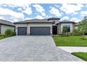 Charming home boasts a three-car garage, stone accents, tile roof, lush landscaping, and a brick paver driveway at 4971 Oyster Pearl St, Bradenton, FL 34211