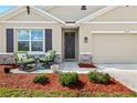 Cozy front porch with chairs, stone accents, and a well-maintained lawn, creating a welcoming curb appeal at 5659 Woodland Sage Dr, Sarasota, FL 34238