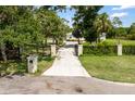 Long private driveway leading to a well-maintained home with beautiful landscaping and a secure gate at 601 Suffolk Cir, Nokomis, FL 34275