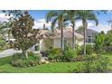Charming home with a lush, landscaped front yard, featuring a variety of plants, trees, and a stone walkway at 7507 Ascot Ct, University Park, FL 34201