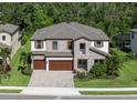 Beautiful two-story home featuring a stone facade, a three-car garage, and lush tropical landscaping at 8932 Isabella Cir, Parrish, FL 34219