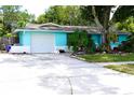 Charming one-story home with a well-maintained lawn, blue paint, white trim, and an attached garage at 1099 6Th Ne Ave, Largo, FL 33770
