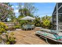 Inviting deck area with comfortable seating, an umbrella-covered dining table, and lush tropical landscaping at 139 Adair Ave, Sarasota, FL 34243