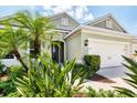 Beautiful exterior of a home with an attached three-car garage, and lush tropical landscaping at 16943 Rosedown Gln, Parrish, FL 34219