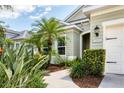 Charming home exterior featuring a well-manicured lawn, tropical landscaping, and a walkway to the front door at 16943 Rosedown Gln, Parrish, FL 34219