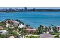 Picturesque aerial view of waterfront home, boasting a terracotta roof amidst lush greenery and the expansive bay at 203 Robin Dr, Sarasota, FL 34236