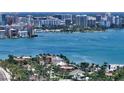 Stunning aerial view of a waterfront home with tile roof surrounded by lush trees and the sparkling bay at 203 Robin Dr, Sarasota, FL 34236