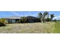 Expansive backyard with a screen-enclosed pool, lush greenery, and ample space for outdoor activities at 217 Mariner Ln, Rotonda West, FL 33947
