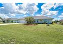 Landscaped front yard with a well-maintained lawn, mature palm trees, and flowering plants at 217 Mariner Ln, Rotonda West, FL 33947