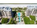 Aerial view of a sparkling blue pool surrounded by palm trees and luxury condominium buildings at 435 L Ambiance Dr # Ph-J, Longboat Key, FL 34228