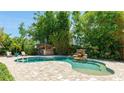 Backyard pool area with waterfall feature, a tiki bar, lounge chairs, mature landscaping, and brick pavers at 5238 Susan Ave, Sarasota, FL 34231