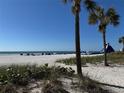 Expansive beach view with beach chairs, palm trees, a waterslide, and clear blue water at 5500 Gulf Blvd # 6248, St Petersburg, FL 33706