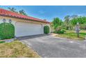 Attractive exterior featuring a red tile roof, well-maintained lawn, mature landscaping, and an attached garage at 5651 Golf Pointe Dr # 5651, Sarasota, FL 34243