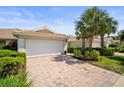 Beautiful home with a tile roof, white garage door, brick driveway, and lush landscaping including palm trees at 5866 Guarino Dr, Sarasota, FL 34238