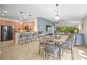 Open-concept living and dining area featuring a modern chandelier, breakfast bar, and sliding doors to the lanai at 5866 Guarino Dr, Sarasota, FL 34238