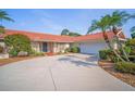 Lovely single-story home boasts a red-tile roof, mature landscaping, and an attached two-car garage at 7804 Broadmoor Pines Blvd, Sarasota, FL 34243