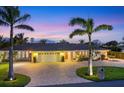Stunning home showcasing a circular driveway, beautiful palms, and illuminated exterior for enchanting evening ambiance at 7913 19Th Avenue W Dr, Bradenton, FL 34209
