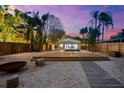 Backyard features a modern pool with a spacious wood deck and stone walkway under a twilight sky at 8234 Midnight Pass Rd, Sarasota, FL 34242