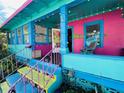 Vibrant two-story building with a brightly colored facade, featuring an inviting porch with eclectic decor at 1019 10Th W Ave, Bradenton, FL 34205