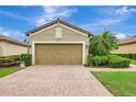 Front of home showcasing a two-car garage, brick driveway, manicured landscaping, and neutral exterior paint at 13108 Torresina Ter, Bradenton, FL 34211