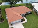 An aerial view shows the tile roof, landscaping, and proximity to a nearby pond at 1654 Waxwing Ct, Venice, FL 34293