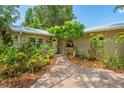 Front exterior view of the home showcasing the home's tropical landscaping and tiled brick walkway at 2630 Bucida Dr, Sarasota, FL 34232