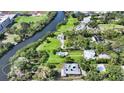 Aerial view of a waterfront property with a pool, lush landscaping, and proximity to a school at 4771 Riverwood Cir, Sarasota, FL 34231