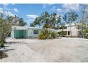 Charming single-story beach home featuring a metal roof and tropical landscaping and shell-covered yard at 5026 Calle Minorga, Sarasota, FL 34242