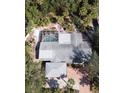 An overhead view of a home featuring a screened pool, lush landscaping, and a gray roof at 5353 Shadow Lawn Dr, Sarasota, FL 34242