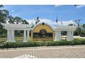 Entrance to the Las Palmas Luxury Condominiums with decorative white pergolas and lush landscaping at 5711 Bentgrass Dr # 19-203, Sarasota, FL 34235