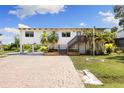 Inviting waterfront home with a well-maintained exterior, brick driveway, and lush tropical landscaping at 6406 Lincoln Rd, Bradenton, FL 34203