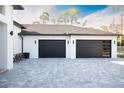 Attached garage with two black doors and modern exterior lighting at 6713 Taneytown St, North Port, FL 34291