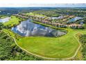 Overhead view of community and golf course featuring multiple residences surrounding a serene lake reflecting the sky at 7911 Grand Estuary Trl # 102, Bradenton, FL 34212