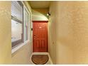 Close up of front door with tan textured walls, transom window, and decorative sun patterned welcome mat at 7911 Grand Estuary Trl # 102, Bradenton, FL 34212