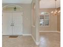 Bright foyer with neutral colors, tiled floor, and transom window over the front door at 8047 Desoto Woods Dr, Sarasota, FL 34243