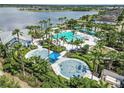 Aerial view of community pool and splashpad, surrounded by lush landscaping and a lake at 11194 Spring Point Cir, Riverview, FL 33579