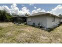 A view of the home's backyard, including a screened enclosure and unkempt lawn at 1036 Arden Nw Ter, Port Charlotte, FL 33948