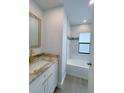 A modern bathroom with an updated tub, shower and granite vanity at 3387 Tupelo Ave, North Port, FL 34286