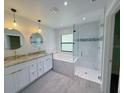 A luxury bathroom with a double sink vanity, modern tub, and a glass-enclosed shower at 3387 Tupelo Ave, North Port, FL 34286