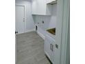 An organized laundry room featuring cabinets, modern tile flooring and a sink at 3387 Tupelo Ave, North Port, FL 34286