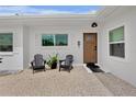Inviting front porch with Adirondack chairs, pea gravel and a stylish wood front door at 404 Bayshore Rd, Nokomis, FL 34275