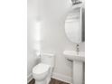 Clean half-bathroom with white fixtures, pedestal sink, round mirror, and modern lighting at 4318 Marina View Way, Cortez, FL 34215