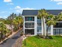 Exterior view of a condo unit featuring a balcony, lush landscaping, and ample natural light at 5600 Beach Way Dr # 201, Sarasota, FL 34242