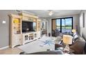 Comfortable living room with large TV, nautical decor, and a view of the lanai and pond at 6515 Grand Estuary Trl # 208, Bradenton, FL 34212