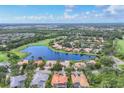 Breathtaking aerial view of a lovely community with a large pond, manicured lawns, tile roofs, and verdant trees at 7214 Marlow Pl, University Park, FL 34201