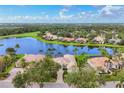 Impressive aerial shot showcasing a waterfront community with a serene lake, palm trees, and beautifully landscaped yards at 7214 Marlow Pl, University Park, FL 34201