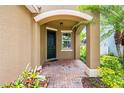 Inviting front porch with arched entry leading to a dark green front door, highlighted by brick pavers at 8437 Nandina Dr, Sarasota, FL 34240