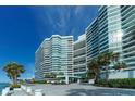 Modern condo exterior with a covered entrance, beautiful landscaping, and blue skies at 988 Blvd Of The Arts # 1016, Sarasota, FL 34236