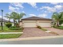 Beige home with lush landscaping, paver driveway, and two-car garage doors in desirable neighborhood at 12515 Garibaldi Ln, Venice, FL 34293
