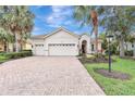 Inviting single-story home with a well-manicured lawn and brick driveway leading to a spacious three-car garage at 12710 Stone Ridge Pl, Lakewood Ranch, FL 34202